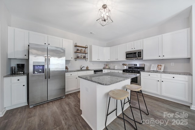 kitchen with a kitchen island, appliances with stainless steel finishes, white cabinets, and stone counters