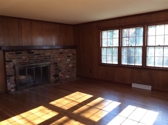 unfurnished living room with wood walls, a brick fireplace, and dark hardwood / wood-style floors