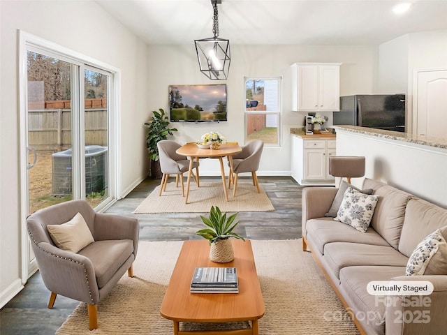 living area with baseboards, dark wood finished floors, and a chandelier