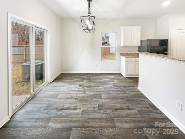 unfurnished dining area with baseboards and dark wood finished floors