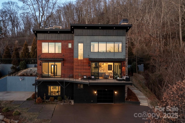 rear view of house featuring a garage, concrete driveway, and stucco siding