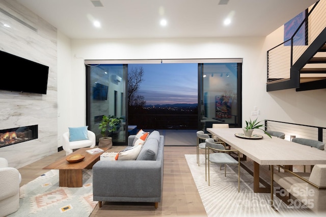 living room featuring recessed lighting, light wood-style flooring, and a high end fireplace