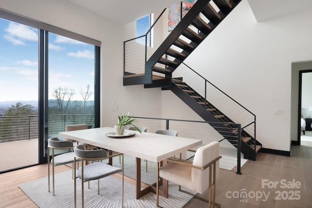 dining area with light wood-style floors, stairs, and baseboards