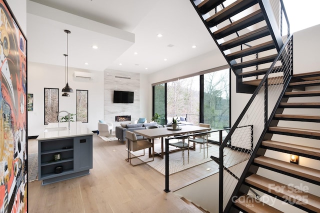 dining room with light wood-style flooring, recessed lighting, a premium fireplace, stairs, and a wall mounted air conditioner