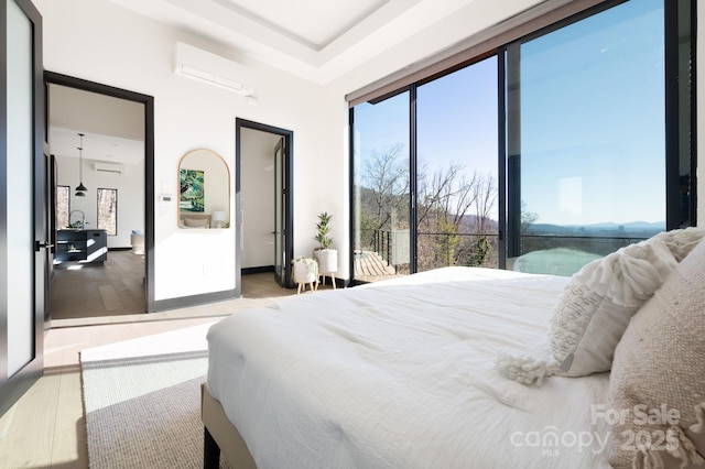 bedroom featuring a wall mounted air conditioner, a water view, and wood finished floors