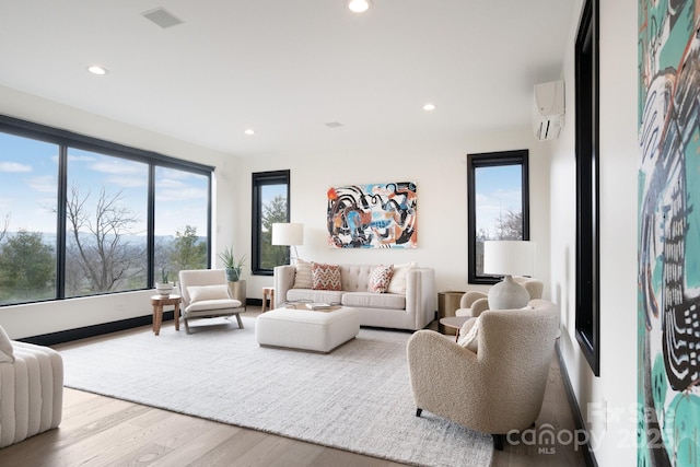 living area featuring recessed lighting, light wood-type flooring, visible vents, and a wall mounted air conditioner