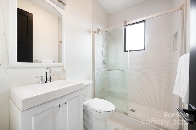 bathroom featuring toilet, a shower stall, and vanity