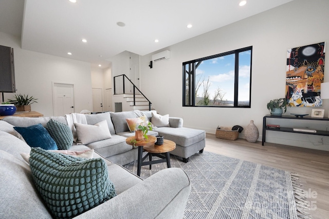 living room featuring stairs, a wall unit AC, light wood-style flooring, and recessed lighting