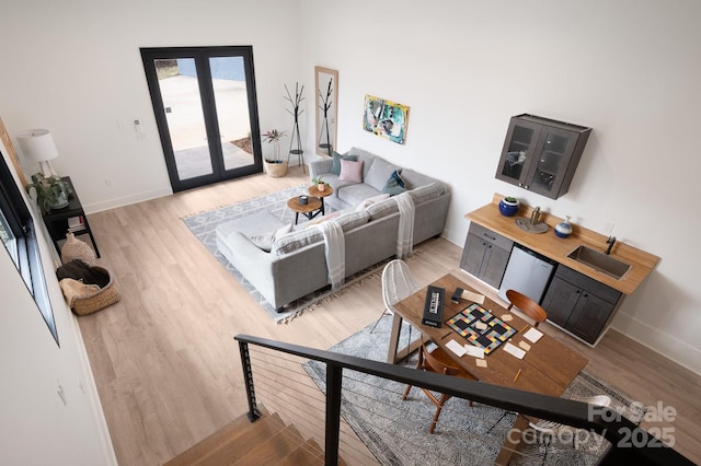 living area featuring light wood-style floors, french doors, and baseboards