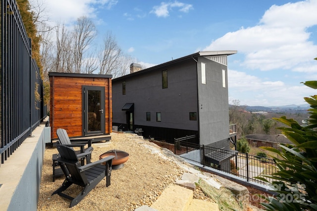 rear view of house with a chimney and fence