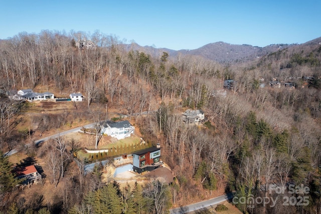 drone / aerial view featuring a wooded view and a mountain view