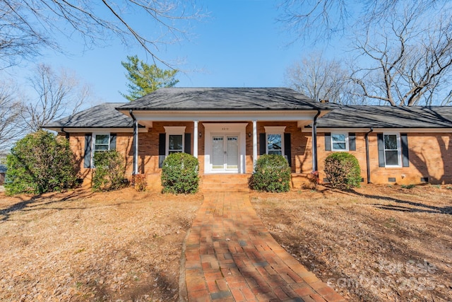 view of front facade featuring crawl space, roof with shingles, a porch, and brick siding