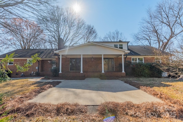 view of front of house featuring covered porch, brick siding, and a chimney