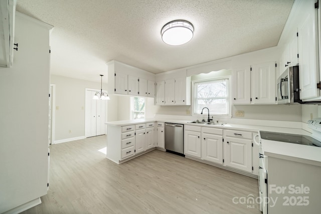 kitchen featuring stainless steel appliances, light wood-style flooring, white cabinets, a sink, and a peninsula