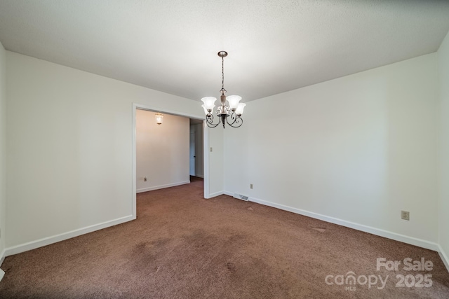 carpeted spare room featuring visible vents, baseboards, and a notable chandelier