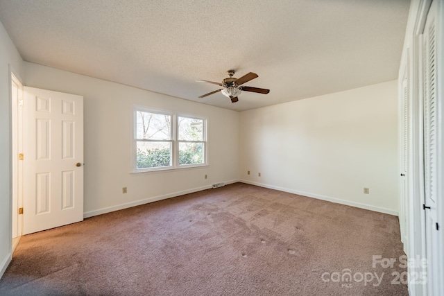 unfurnished bedroom featuring carpet, visible vents, a textured ceiling, and baseboards