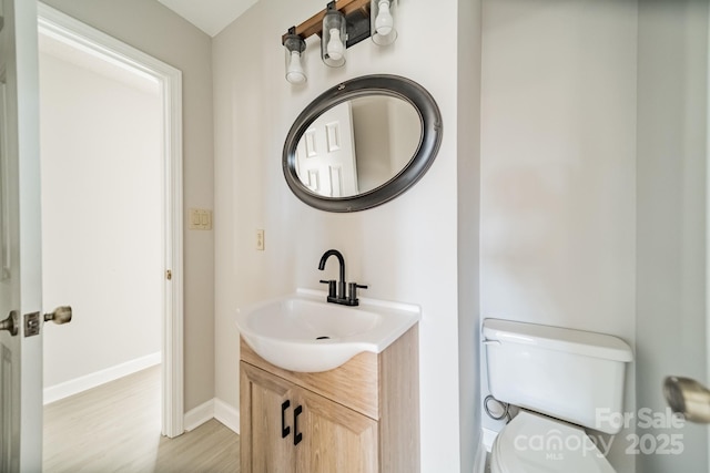 bathroom with baseboards, vanity, toilet, and wood finished floors