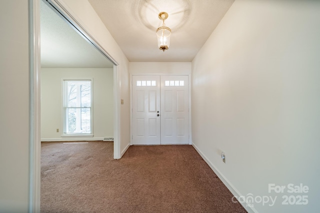 foyer entrance with carpet floors, visible vents, and baseboards