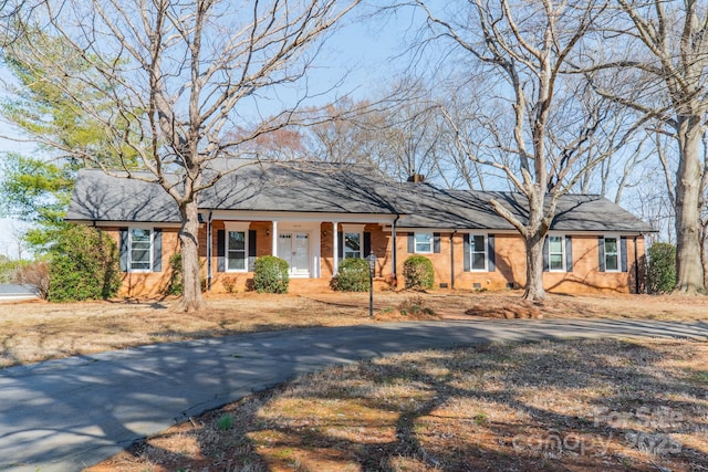 single story home featuring brick siding, driveway, and a chimney