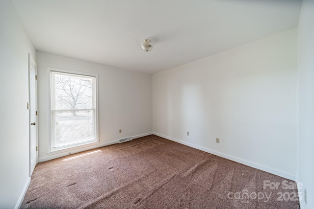 carpeted spare room with baseboards and visible vents