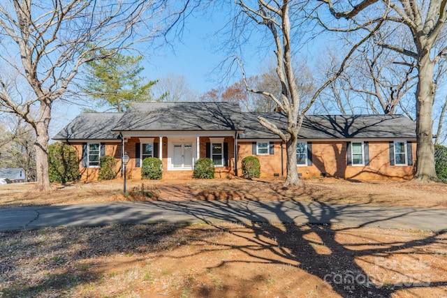 ranch-style house with driveway, a porch, and brick siding