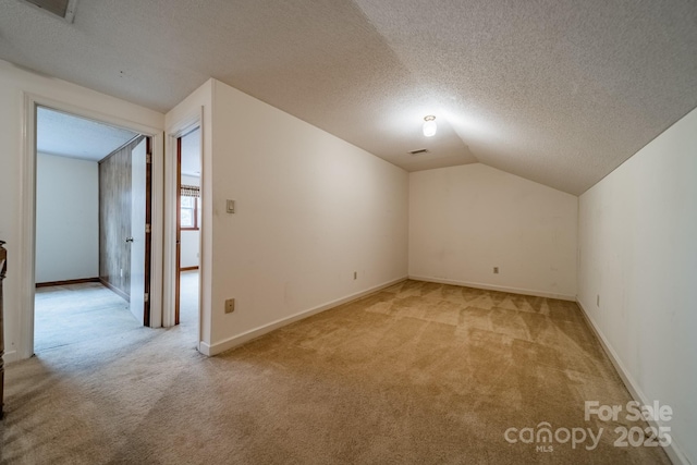 additional living space with lofted ceiling, visible vents, a textured ceiling, and light colored carpet