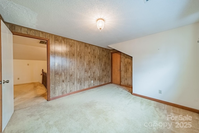 spare room with wood walls, carpet, visible vents, and a textured ceiling