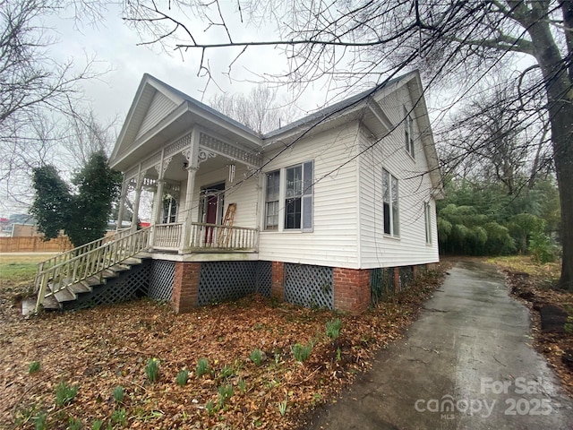 view of side of home featuring covered porch