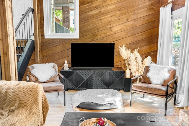 living area with stairs, wood walls, and light wood-type flooring