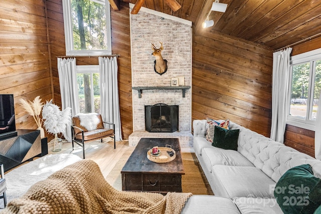 living area featuring high vaulted ceiling, wooden ceiling, wooden walls, light wood-type flooring, and a brick fireplace