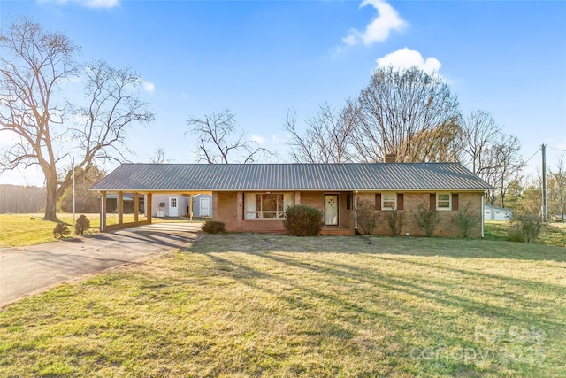 ranch-style house featuring driveway, a chimney, metal roof, an attached carport, and a front lawn