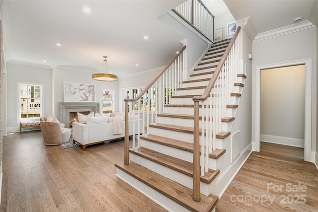 stairs featuring crown molding and hardwood / wood-style flooring
