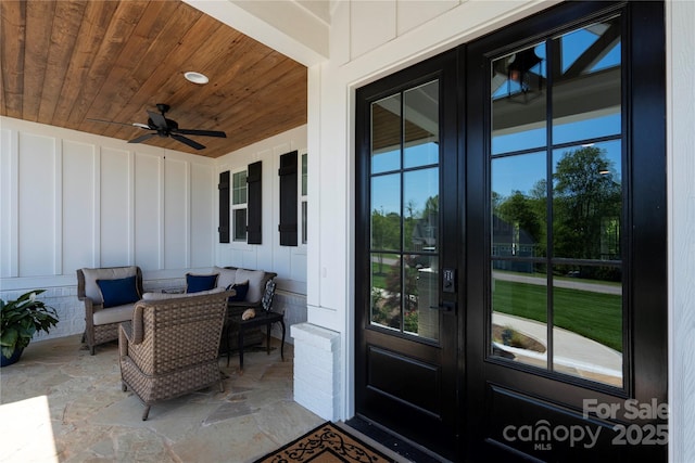 view of exterior entry with board and batten siding, french doors, and a ceiling fan