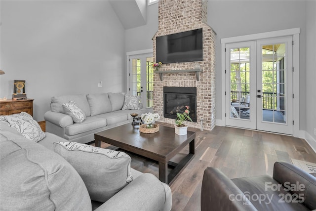 living room featuring visible vents, wood finished floors, french doors, a fireplace, and high vaulted ceiling