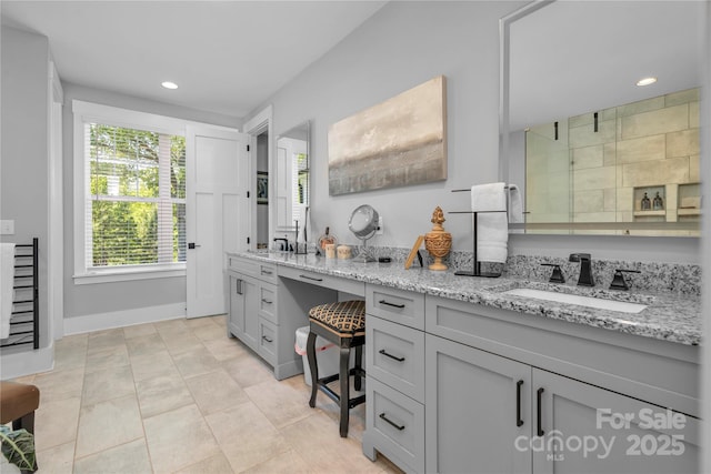 kitchen featuring recessed lighting, gray cabinets, a sink, and light stone countertops