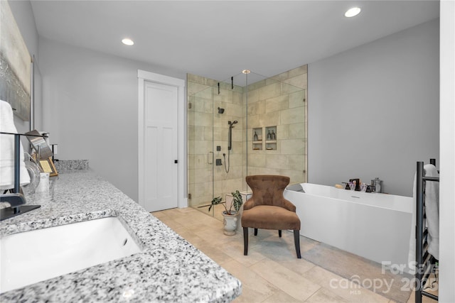 bathroom with a freestanding tub, recessed lighting, a sink, double vanity, and a stall shower