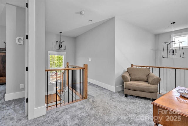 sitting room featuring carpet, baseboards, and an upstairs landing