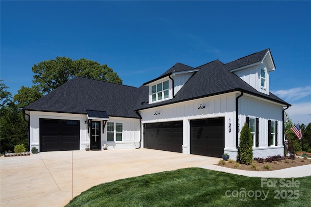 modern farmhouse with a shingled roof, board and batten siding, a front yard, a garage, and driveway