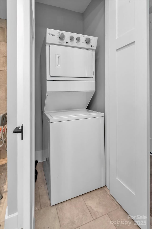 laundry room with light tile patterned floors and stacked washer / dryer