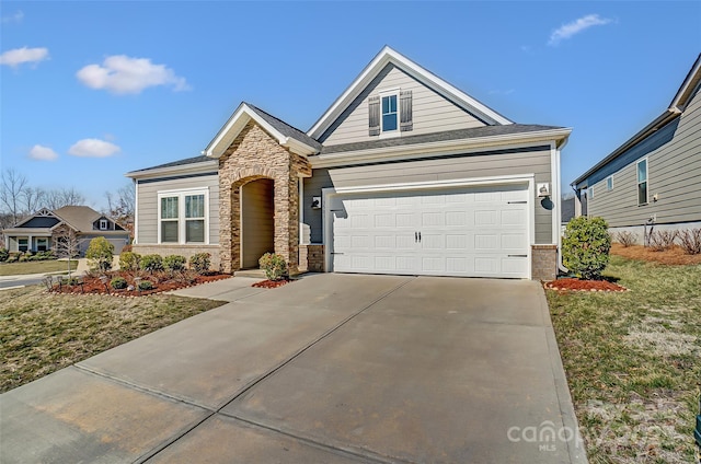 view of front facade with a garage, a front yard, stone siding, and driveway