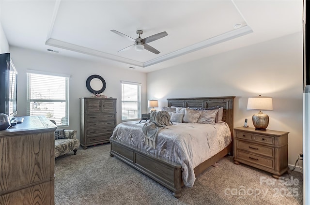 bedroom featuring multiple windows, carpet flooring, a raised ceiling, and visible vents