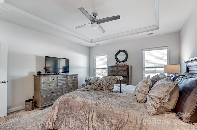 bedroom featuring light carpet, baseboards, visible vents, a raised ceiling, and a ceiling fan