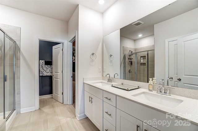 full bathroom with a stall shower, visible vents, a walk in closet, and a sink