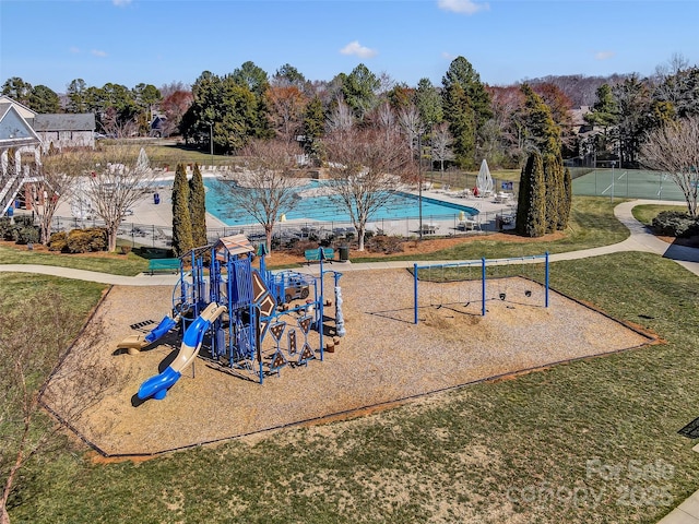 community jungle gym with a community pool, fence, and a yard