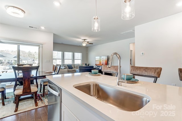 kitchen featuring a sink, pendant lighting, light countertops, and stainless steel dishwasher