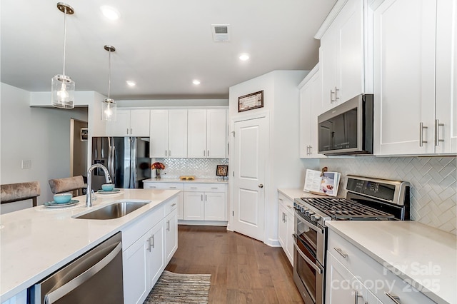 kitchen featuring appliances with stainless steel finishes, white cabinets, and hanging light fixtures