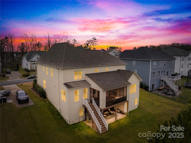 back of property featuring roof with shingles, stairway, a sunroom, a residential view, and driveway