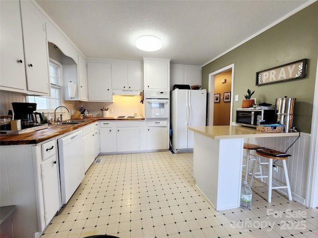 kitchen featuring white cabinetry, white appliances, and a kitchen bar