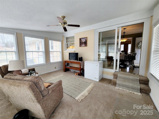 living room with ceiling fan, built in features, light colored carpet, and a textured ceiling