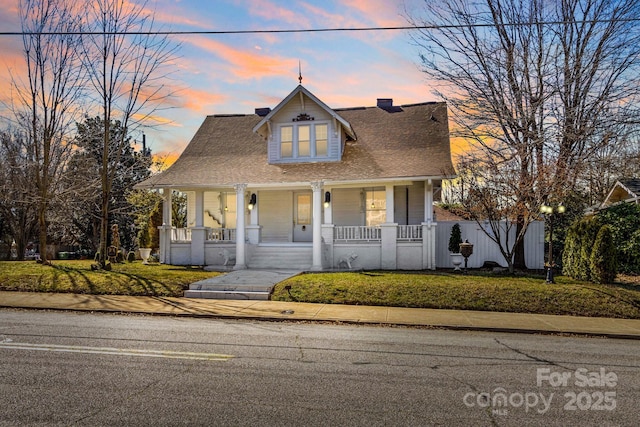 view of front of house with covered porch, fence, and a front yard